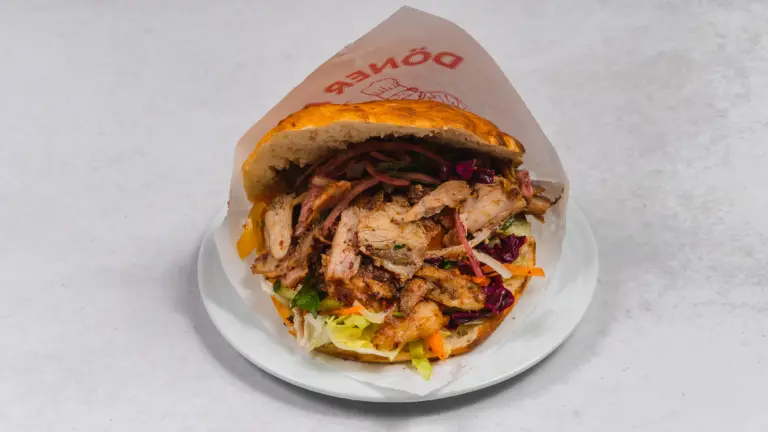 Gefüllter Döner mit gegrilltem Fleisch und gemischtem Salat in Fladenbrot auf weißem Teller